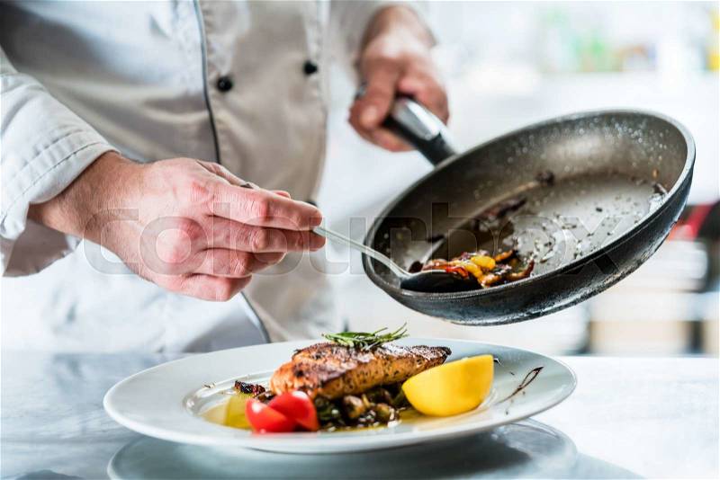 Chef finishing food in his restaurant kitchen, stock photo