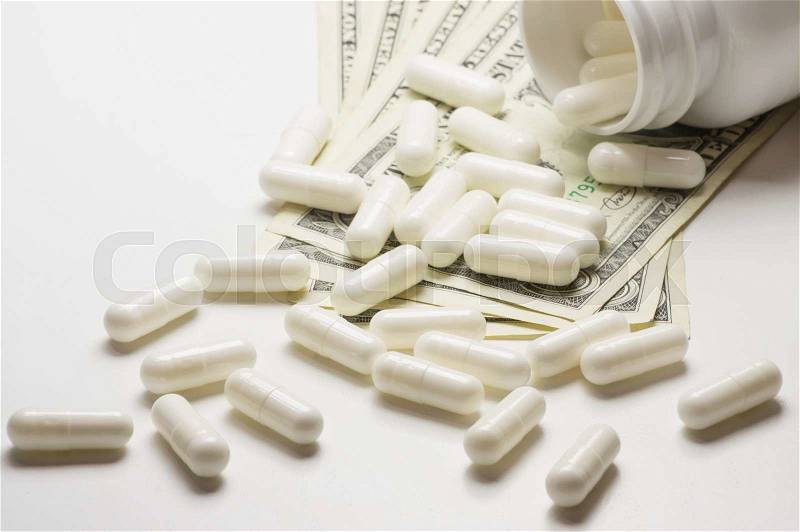 Pills over money. The high cost of healthcare, stock photo