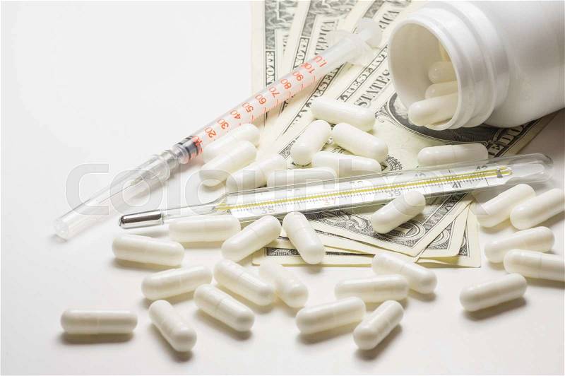 Pills, syringe and thermometer over money. The high cost of healthcare, stock photo