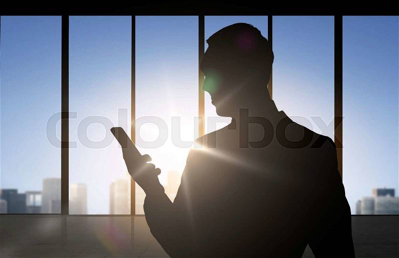 Business and people concept - silhouette of businessman with smartphone over office window background, stock photo
