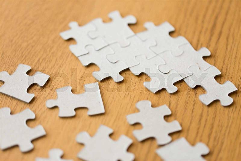 Business and connection concept - close up of puzzle pieces on wooden surface, stock photo