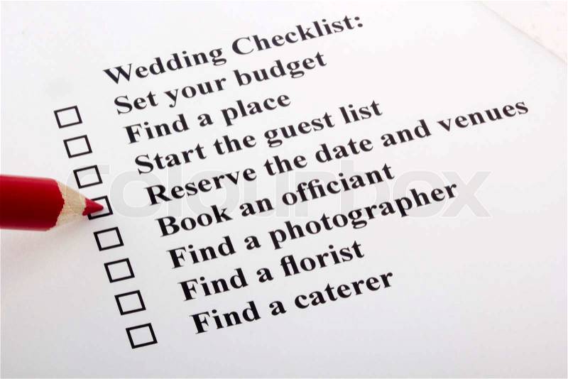 Red pencil checking a box on a wedding checklist, stock photo