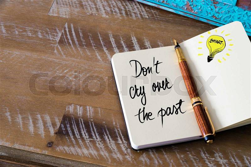 Handwritten text Don\'t Cry Over The Past with fountain pen on notebook. Concept image with copy space available, stock photo