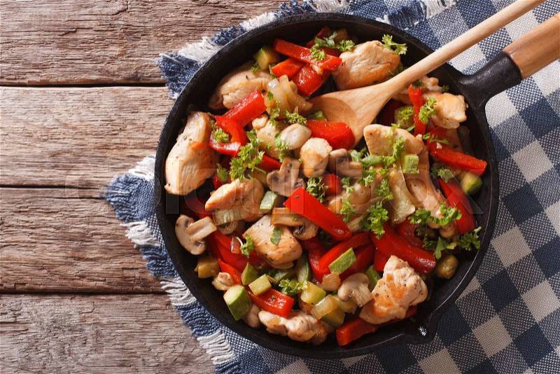 Stir Fry Chicken with mushrooms, peppers and zucchini on a frying pan close-up. Horizontal view from above , stock photo