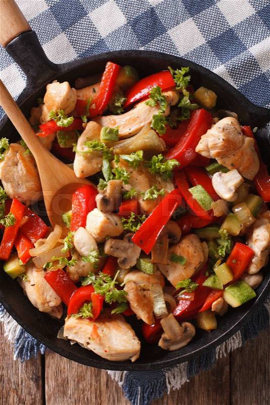 Chicken breast fried with mushrooms, peppers and zucchini on a frying pan closeup. vertical view from above\, stock photo