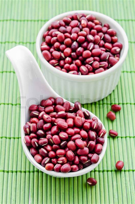 Azuki beans , red beans in white spoon on green bamboo mat, stock photo