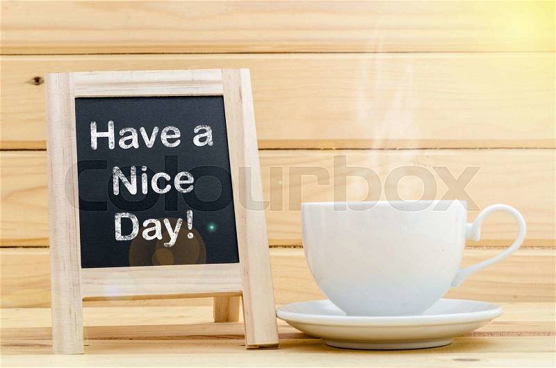Have a nice day word on chalkboard and coffee in white cup with smoke. Day light, stock photo