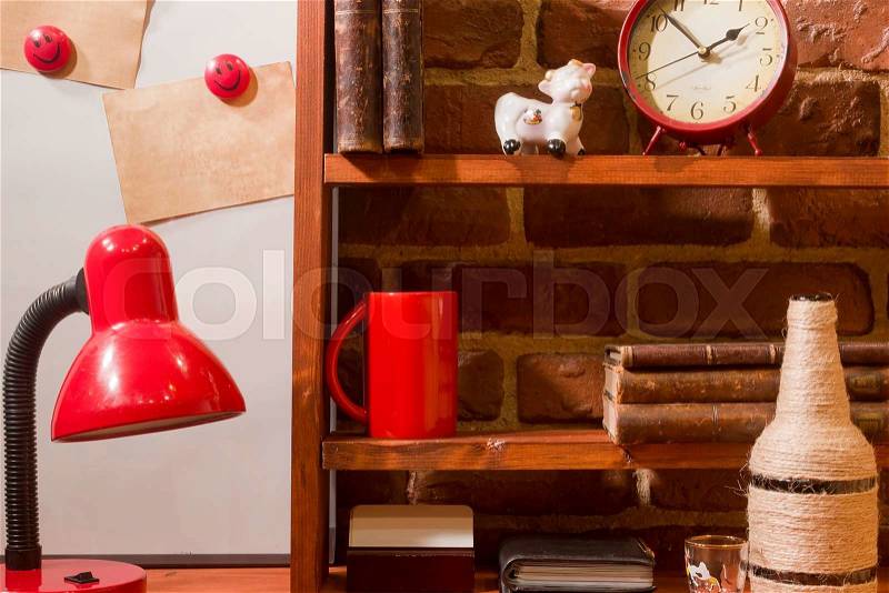 Vintage books coffee cup and desk lamp on the table. Wooden shelf on a background of the brickwork, stock photo