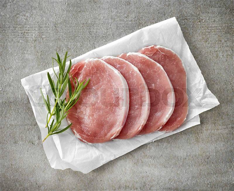 Fresh raw pork and rosemary on white wrapping paper, stock photo