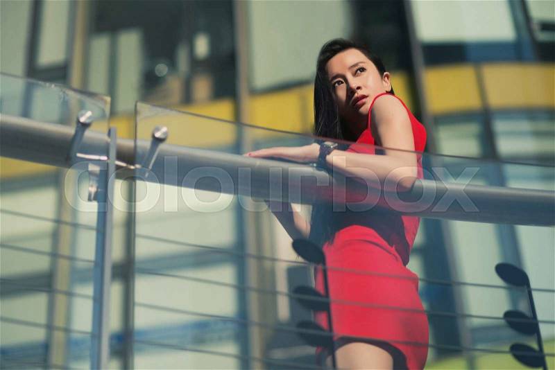 Beautiful Asian girl model in red dress posing at the modern music note style city background, stock photo