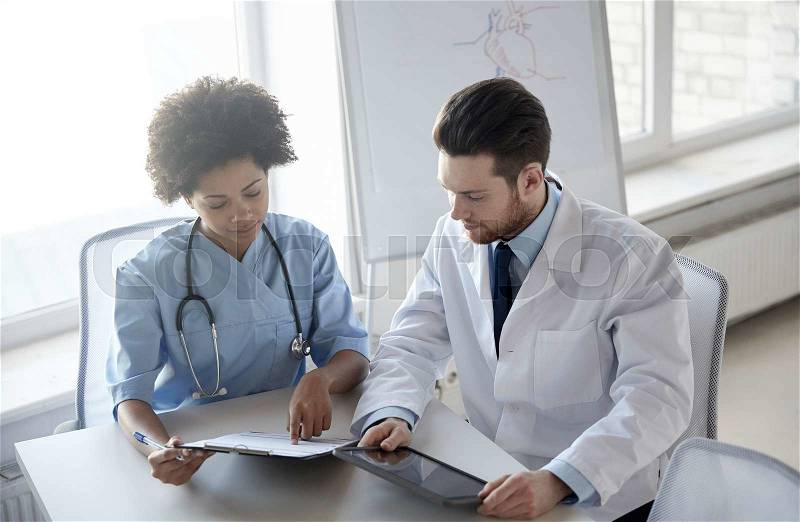 Health care, people, technology and medicine concept - doctor and nurse with tablet pc computer and clipboard meeting and discussing something at hospital, stock photo