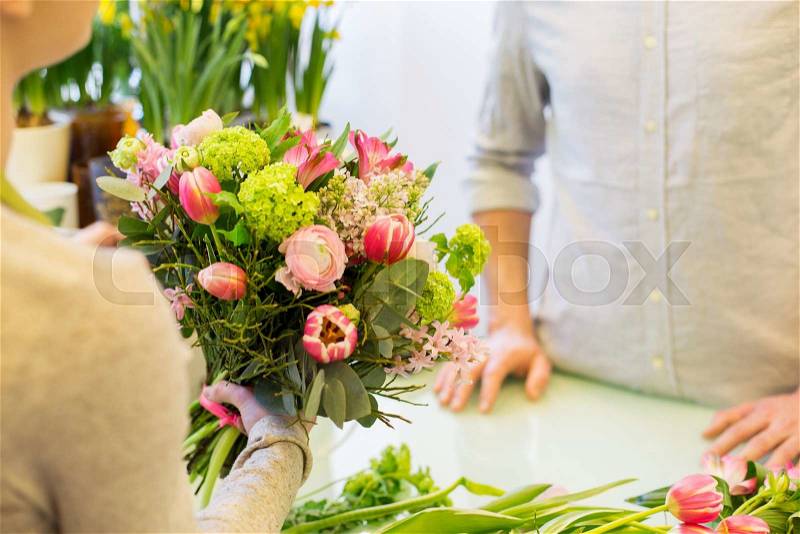People, shopping, sale, floristry and consumerism concept - close up of florist woman making bouquet for and man or customer at flower shop, stock photo