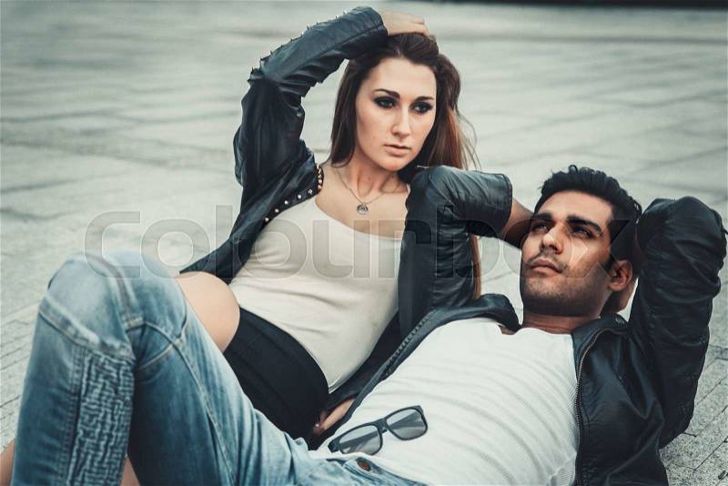 Young trendy man and woman models posing of the modern street. Fashion Style. lie on the floor, stock photo