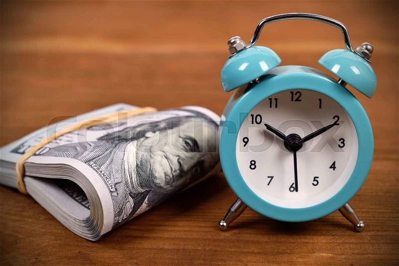 Business concept with dollar and alarm clock on wooden board, stock photo