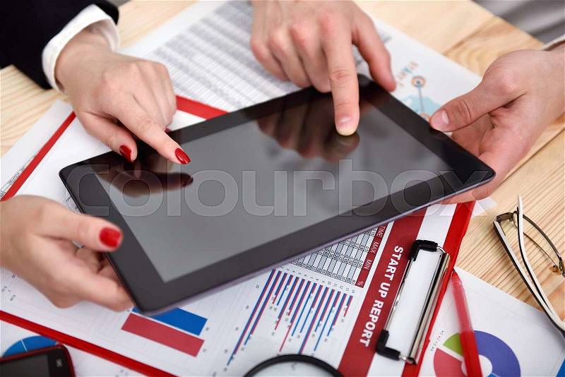 Co worker hands during discussion of data in digital tablet at meeting, stock photo