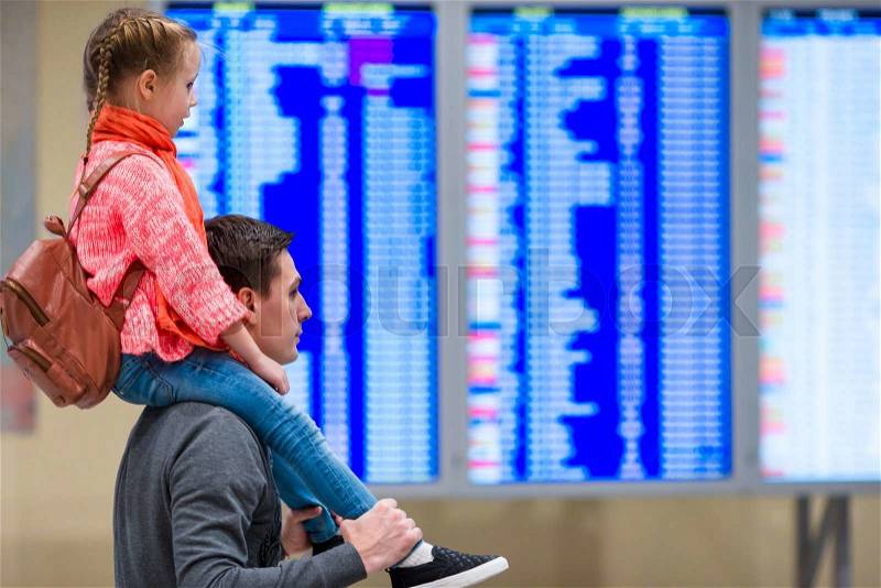 Little girl with her father background flight information at airport, stock photo