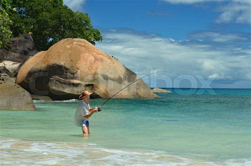 Elderly man fishing in the sea with a fishing rod, stock photo