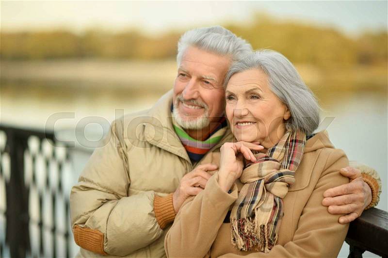 Happy senior couple near river at autumn ,blurred background, stock photo