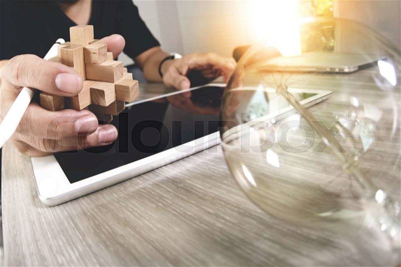 Creative hand showing wood puzzle and light bulb with laptop computer and tablet computer as design concept, stock photo