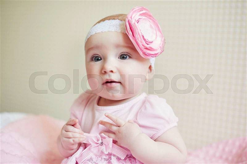 Portrait of cute little baby girl with pink bow flower on her head, stock photo