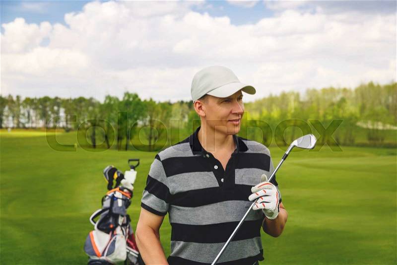Portrait of male golfer choosing a golf club at golf course, stock photo