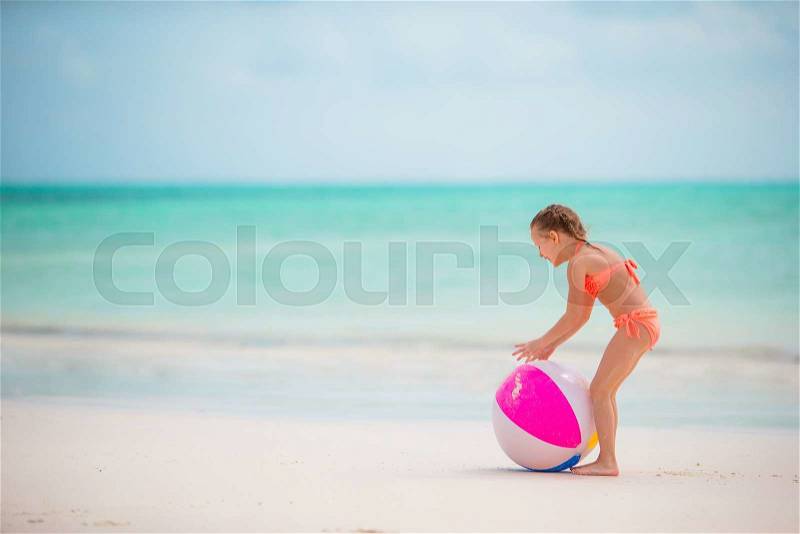 Little adorable girl playing on white beach with air ball, stock photo