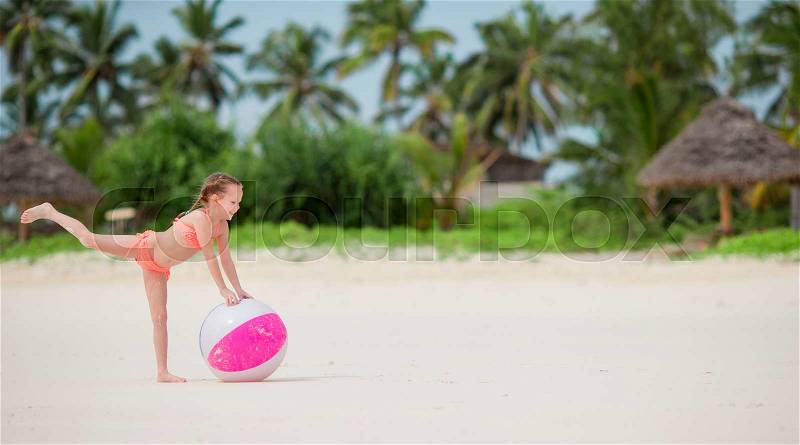 Little adorable girl playing on white beach with air ball, stock photo