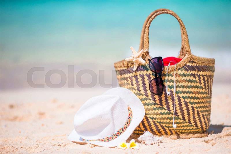 Beach accessories - bag, straw hat, sunglasses on white beach, stock photo