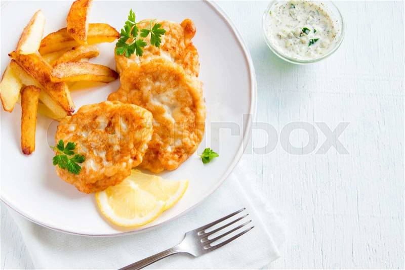 Homemade fish cakes with french fries on white wooden background with copy space, stock photo