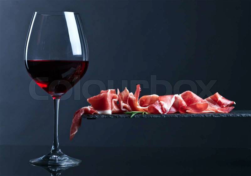 Jamon with red wine on a black background, stock photo