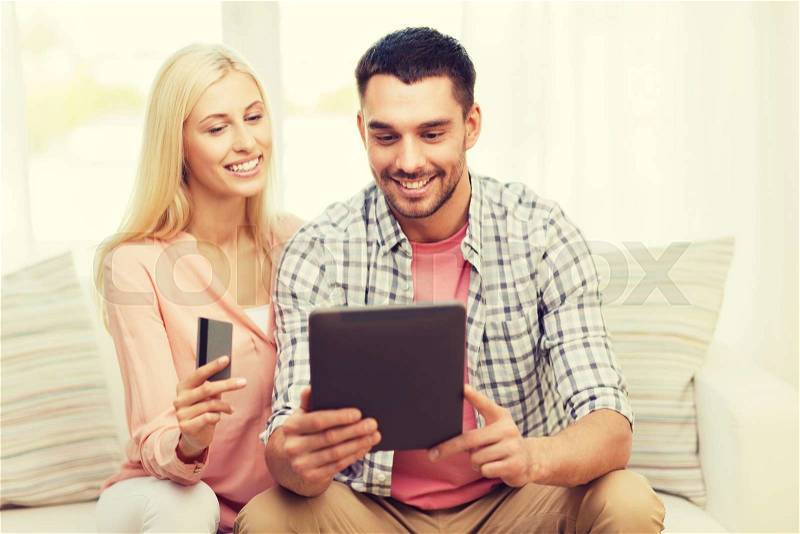 Technology, people, e-money and commerce concept - smiling happy couple with tablet pc computer and credit or bank card shopping online at home, stock photo