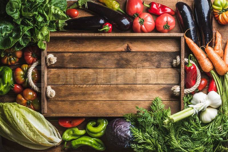 Fresh raw vegetable ingredients for healthy cooking or salad making with rustic wooden tray in center, top view, copy space. Diet or vegetarian food concept, horizontal composition, stock photo