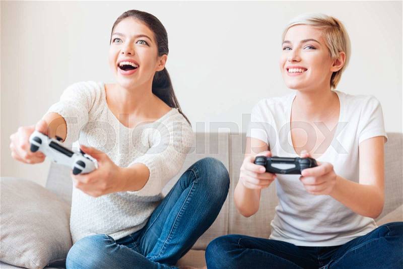 Two happy women playing video games , stock photo