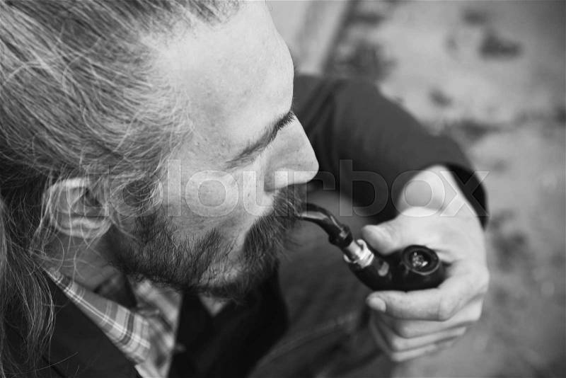 Man smoking pipe, black and white photo with selective focus, stock photo