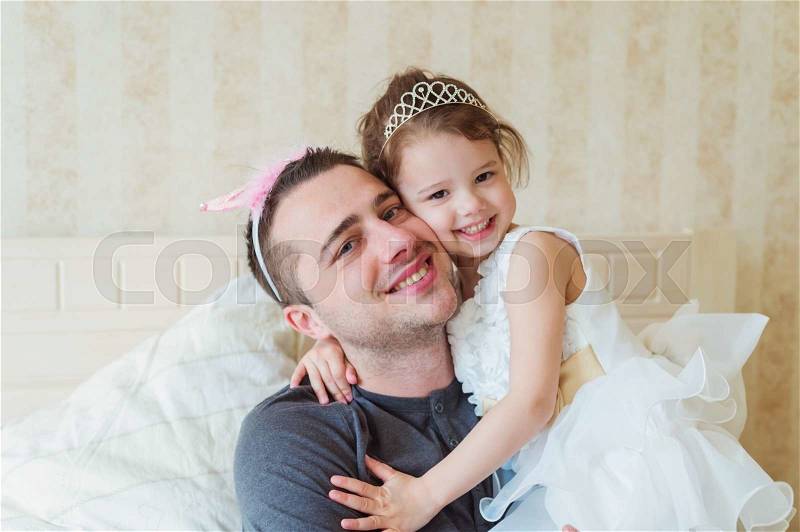 Cute little girl in princess dress with her father wearing crowns, smiling, stock photo