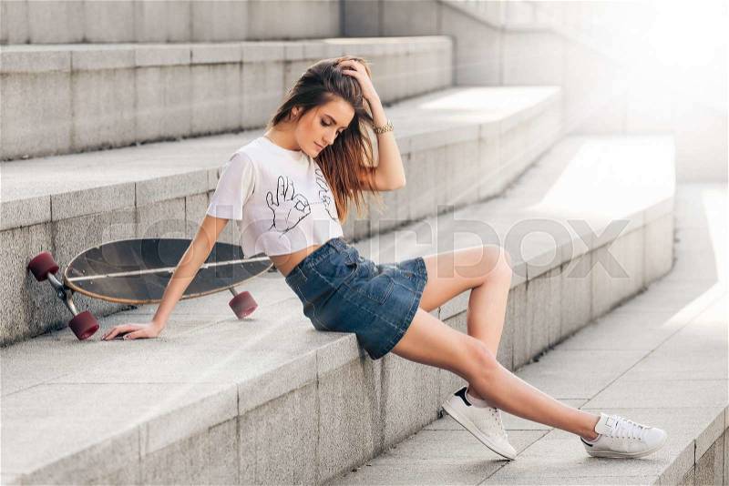 Outdoor portrait of young beautiful fashionable girl posing on concrete stairs of the city. Model wearing stylish clothes. Girl looking aside. Female stylish fashion. City lifestyle, stock photo