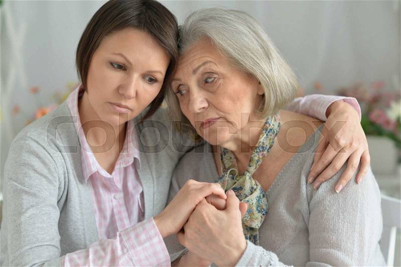 Miserable senior mother and adult daughter together, stock photo