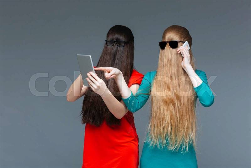 Two angry young women covered face with long hair and fighting , stock photo
