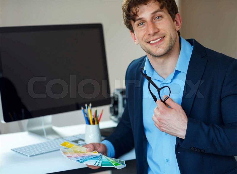 Young man looking to a color paint palette at home office, stock photo