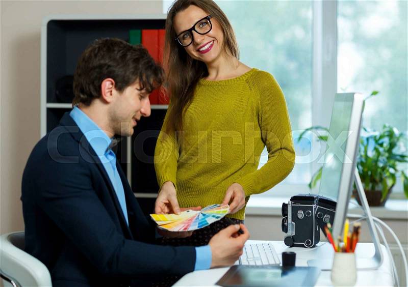 Young colleague - man and woman looking to a color paint palette at home office, modern business concept, stock photo