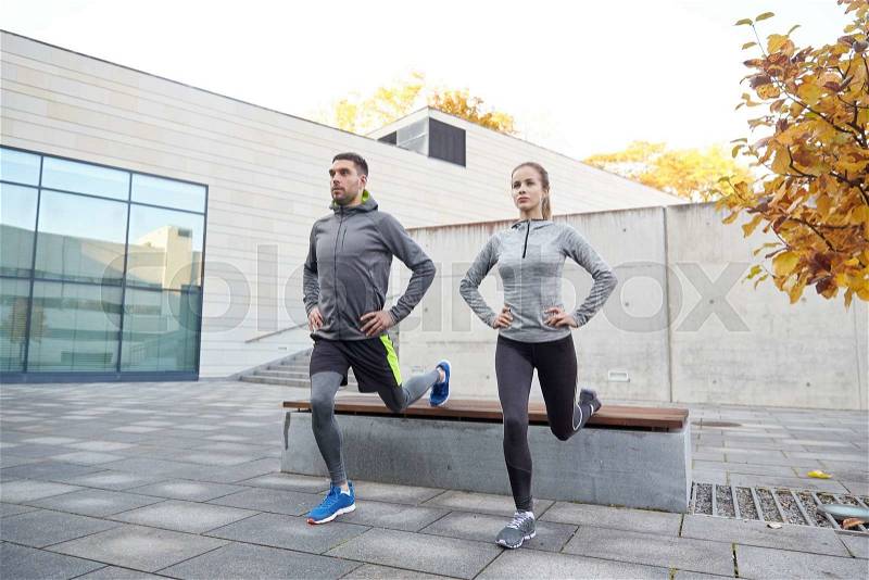 Fitness, sport, people, exercising and lifestyle concept - couple doing lunge exercise on city street, stock photo