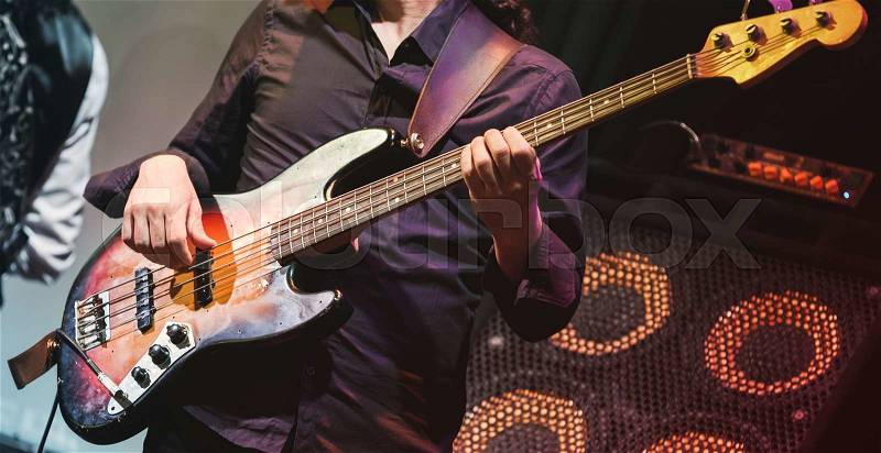 Rock music concert, bass guitar player on a stage, selective focus, stock photo
