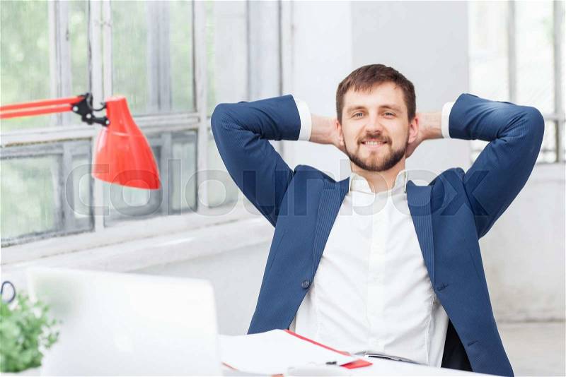 The smiling male office worker resting against white office , stock photo