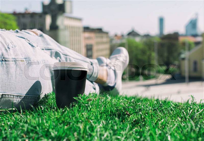 Woman resting on the grass with cup of coffee, stock photo