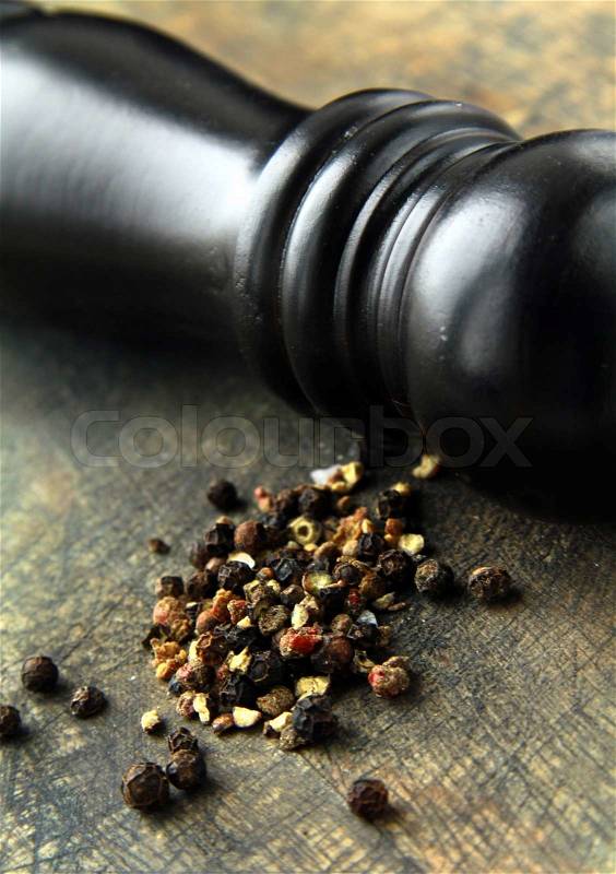 Black pepper and black pepper-mill on a wooden board, stock photo