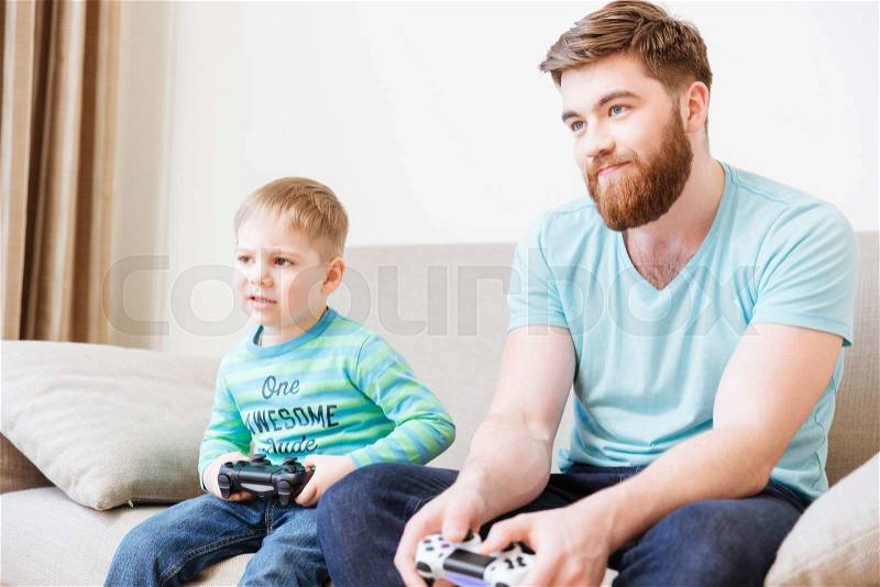 Sad unhappy dad and son playing computer games at home, stock photo