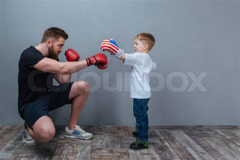 Father and little son working out in boxing gloves together, stock photo