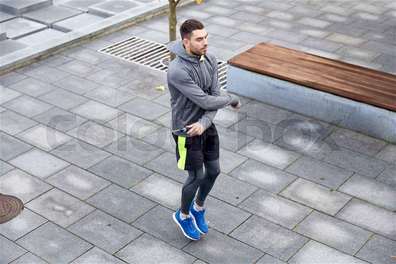 Fitness, sport, people, exercising and lifestyle concept - man skipping with jump rope outdoors, stock photo