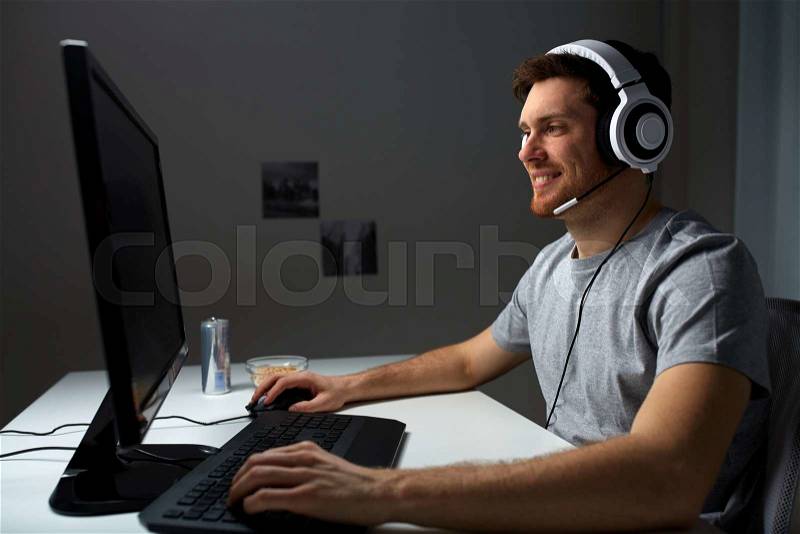 Technology, gaming, entertainment, let\'s play and people concept - happy young man in headset with pc computer playing game at home and streaming playthrough or walkthrough video, stock photo