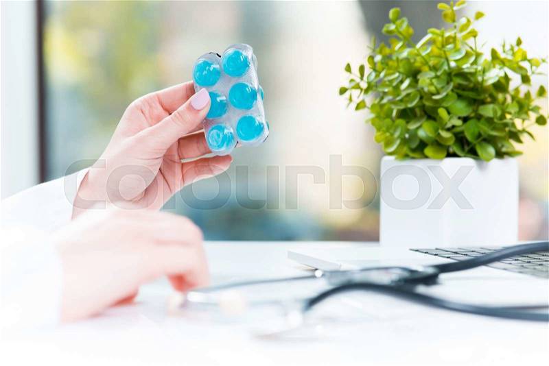The hand of female medicine doctor holding tablet blister closeup. Medical prescription, pharmacy or insurance concept. Giving or showing medications to patient, stock photo